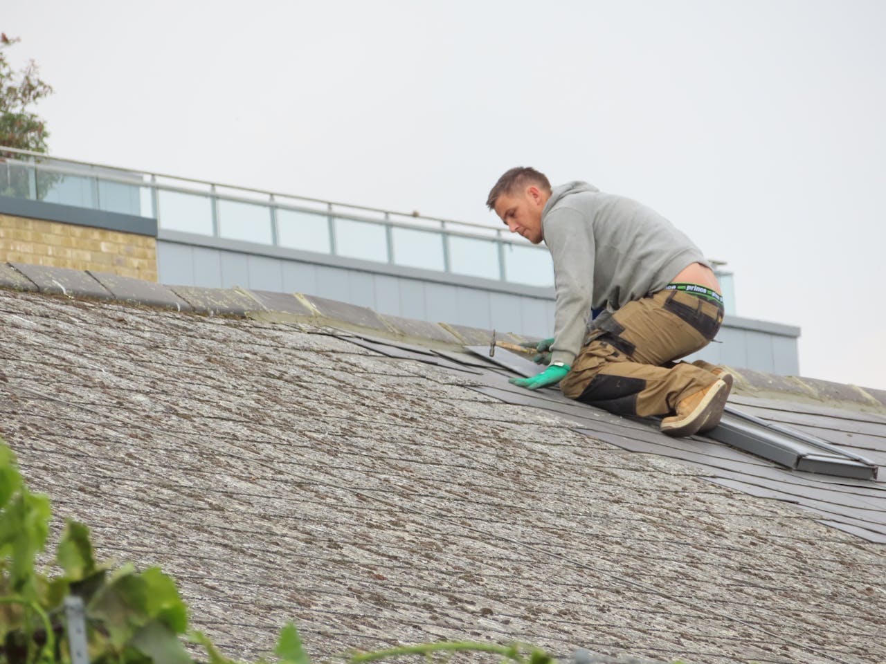 services-10 Construction worker installing shingles on a rooftop. Outdoor building maintenance.